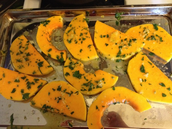 Squash rounds on baking sheet ready to go into the oven, covered with garlic, oil, herb and orange juice marinade